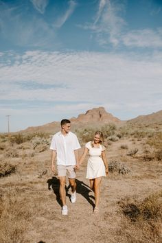 a man and woman walking in the desert holding hands