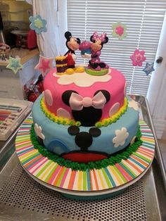 a mickey mouse and minnie mouse cake on top of a table in front of a window