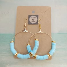 a pair of blue and gold hoop earrings sitting on top of a cardboard card board