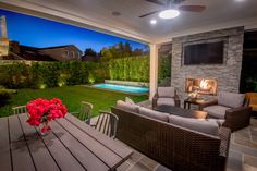 an outdoor living area with couches, tables and a television on the outside wall