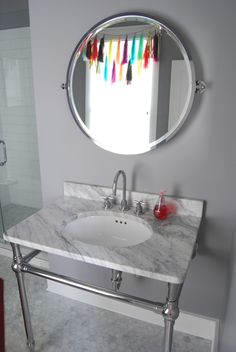 a bathroom with a sink, mirror and colorful streamers on the window sill