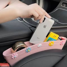 a person holding an iphone in their car seat with the phone holder attached to it