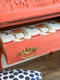 an orange painted desk with drawers and polka dot chair cushion on the floor next to it