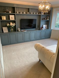 a living room filled with furniture and a flat screen tv on top of a wooden shelf