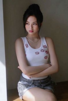 a young woman sitting on top of a wooden floor next to a wall with her arms crossed