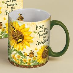 two coffee mugs sitting next to each other with sunflowers on the side