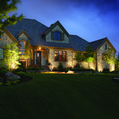 a house lit up at night with lights on the front and side of the house