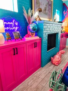 a living room with pink and blue walls, wooden flooring and colorful decorations on the fireplace