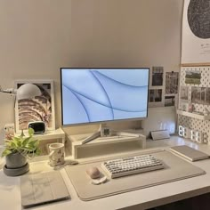 a computer monitor sitting on top of a desk next to a keyboard, mouse and plant