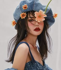 a woman wearing a blue hat with flowers on it's head and her hair blowing in the wind