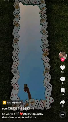 the reflection of a person holding a cell phone in front of a mirror with playing cards on it