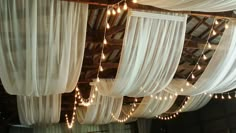 the ceiling is covered with white drapes and string lights