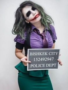 a woman dressed as the joker holding a sign