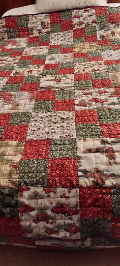 a bed with a red, green and white quilt on it's headboard