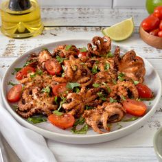 a white plate topped with octopus and tomatoes