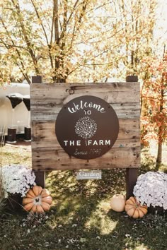 a welcome sign for the farm surrounded by pumpkins