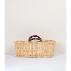 a wicker basket sitting on top of a white table next to a brown beaded bracelet