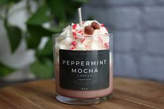 a glass cup filled with whipped cream and candy canes on top of a wooden table