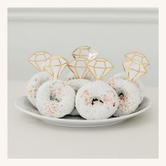 a white plate topped with donuts covered in sprinkles and gold decorations