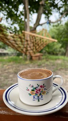 a cup of coffee sitting on top of a saucer next to a hammock