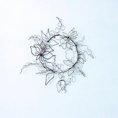 a wire wreath with flowers and leaves on a white background