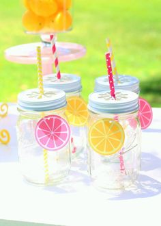 three mason jars with straws and orange slices on them sitting on a table outside