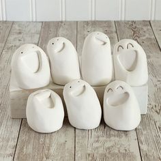 five white ceramic figurines sitting on top of a wooden table next to each other