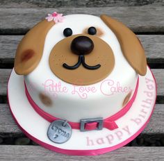 a cake decorated with a dog's face and name is on a wooden bench