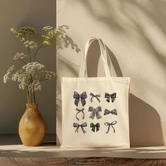 Our Black Bow Tote Bag is a cute Coquette Tote Bag that makes the perfect Cute Gift for Friend Birthday that's a great reusable bag. 𝐌𝐀𝐓𝐂𝐇𝐈𝐍𝐆 𝐒𝐇𝐈𝐑𝐓 & 𝐏𝐈𝐋𝐋𝐎𝐖 𝐀𝐕𝐀𝐈𝐋𝐀𝐁𝐋𝐄 (𝐋𝐈𝐍𝐊𝐒 Shirt:  https://www.etsy.com/listing/1733265141/coquette-bow-tee-oversized-comfort Pillow:  https://www.etsy.com/listing/1733265001/black-bows-pillow-coquette-aesthetic 𝐏𝐑𝐎𝐃𝐔𝐂𝐓 𝐃𝐄𝐓𝐀𝐈𝐋𝐒 🌸100% cotton canvas 🌸Size: 15" x 16" 🌸Heavy fabric (12 oz/yd² (406.9 g/m 🌸Features 20" handles 🌸Sewn-in label 🌸Kindly be aware that slight color variations may occur due to the display settings on your phone, computer, or tablet.  Color variations may also occur due to the printing process. 𝐏𝐑𝐎𝐃𝐔𝐂𝐓𝐈𝐎𝐍 & 𝐒𝐇𝐈𝐏𝐏𝐈𝐍𝐆 𝐓𝐈𝐌𝐄𝐒 🌸2 - 7 business day production time. This do Cute Beige Shoulder Bag As Gift, Cute Large Capacity Shoulder Bag For Gift, Cute Reusable School Bags, Cute Canvas Shoulder Bag For Gifts, Cute Rectangular Shoulder Bag - Gift Idea, Cute Rectangular Shoulder Bag As Gift, Cute Rectangular Shoulder Bag For Gifts, Beige Canvas Shoulder Bag As Gift, Cute Canvas Shoulder Bag For Gift