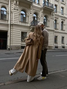 a man and woman are walking down the street in front of an old style building