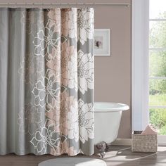 a bath tub sitting next to a shower curtain in a bathroom with a flower pattern on it