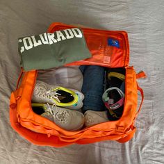 an orange duffel bag filled with shoes and other items