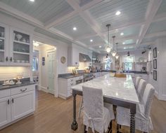 a large kitchen with white cabinets and marble counter tops, along with an island in the middle