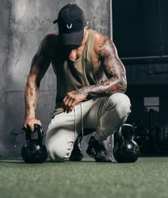 a man squatting down with two kettles in his hands and one on the ground