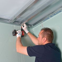 a man is working on the ceiling with a drill and screwdriver in his hand