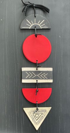 three red, white and black circles hanging from a hook on a gray wall with leather cord