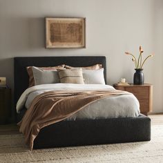 a bedroom with a bed, nightstands and pictures on the wall above it is shown