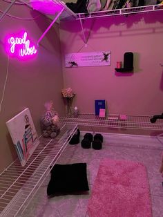 a room with pink walls and shelving in the corner is lit by neon lights