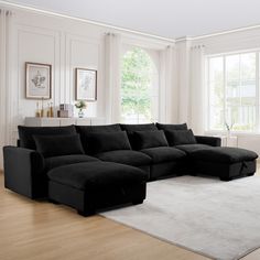 a large black sectional sofa in a living room with hardwood flooring and white walls