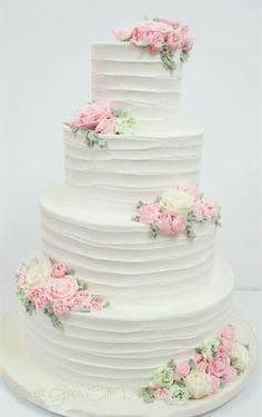 a white wedding cake with pink and white flowers on the top tier, sitting on a plate