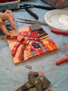 a person cutting up some pieces of glass on a table with pliers and other tools