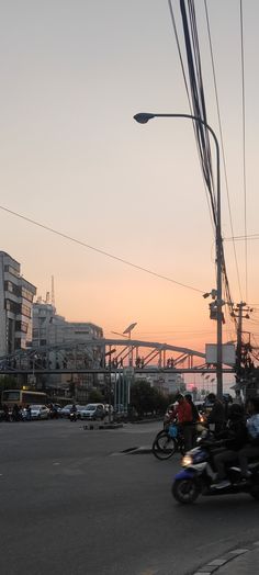 people riding motorcycles down the street at sunset