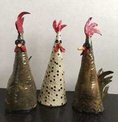 three ceramic roosters sitting on top of a wooden table