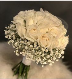 a bouquet of white roses and baby's breath on a fur - lined surface