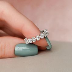 a woman's hand holding a ring with five diamonds on the middle of it