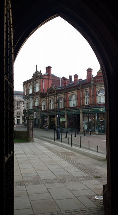 an arch in the middle of a street with buildings on both sides and shops to the side