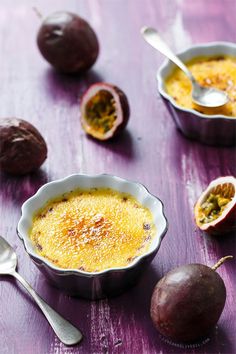 two bowls filled with pudding and spoons on top of a wooden table next to fruit