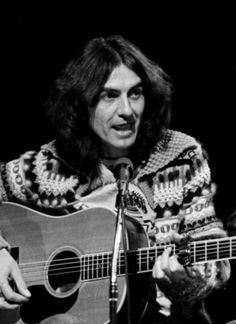 an old photo of a man holding a guitar in front of a microphone and singing