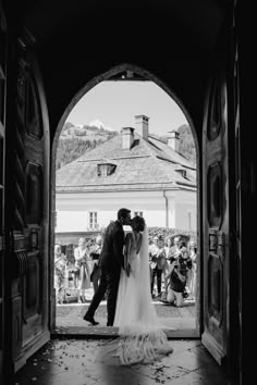 a bride and groom kissing in an open doorway