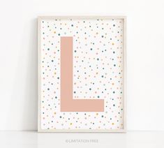 a white frame with dots and a pink letter l on the bottom, in front of a white wall